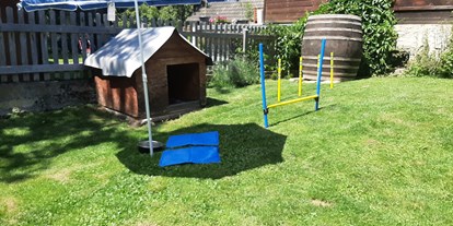 Hundehotel - Sitzplatz im Garten - Der Garten gut eingezäunt mit Hunderhütte und Spielelandschaft  - Ferienhaus Harmonie